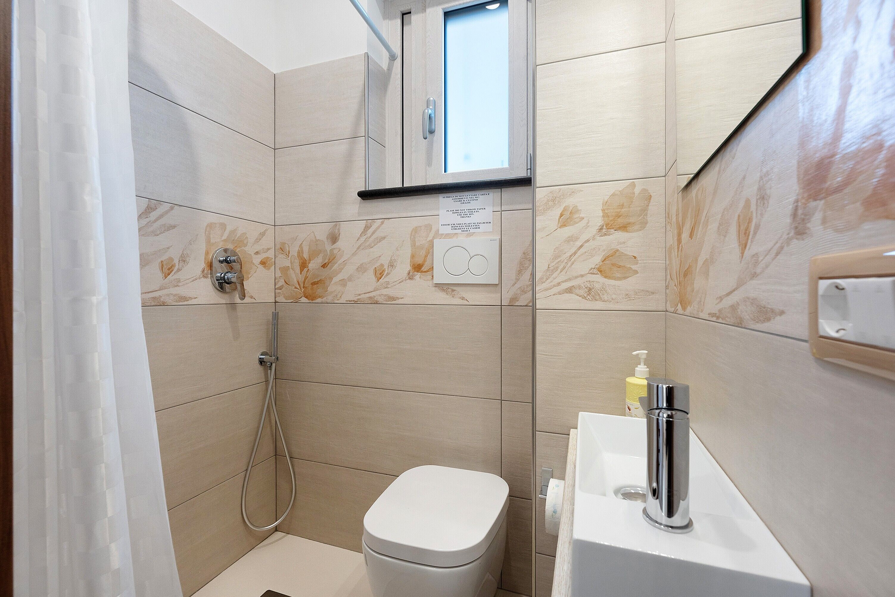 Une salle de bain équipée d’une douche, de toilettes, d’un lavabo et d’un miroir au-dessus du lavabo.