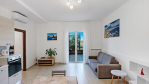 A modern living room with a sofa, a dining table, and a kitchen area with an oven. - Casa Vacanza Annì with Wi-Fi and Air Conditioning (Vico Equense)