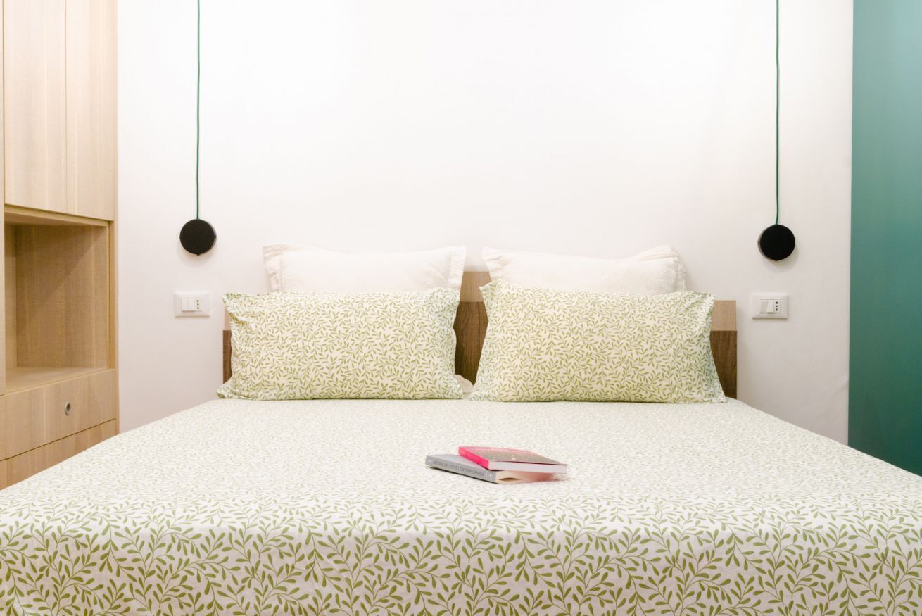 A neatly made bed with a patterned bedspread, two pillows with a leaf pattern, and two round wall decorations.