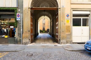 Une rue étroite, avec un passage en arc, qui mène à un bâtiment sur lequel est apposée une pancarte indiquant une zone où le stationnement est interdit.