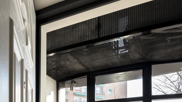 A modern entrance with a black-framed glass door, white orchids in planters, and a view of buildings outside. - Two Apartments Combined into One Space; 8 people (Milano)