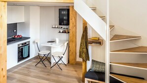 A loft-style room with a kitchen area, a dining table with chairs, and a staircase. - Two Apartments Combined into One Space; 8 people (Milano)