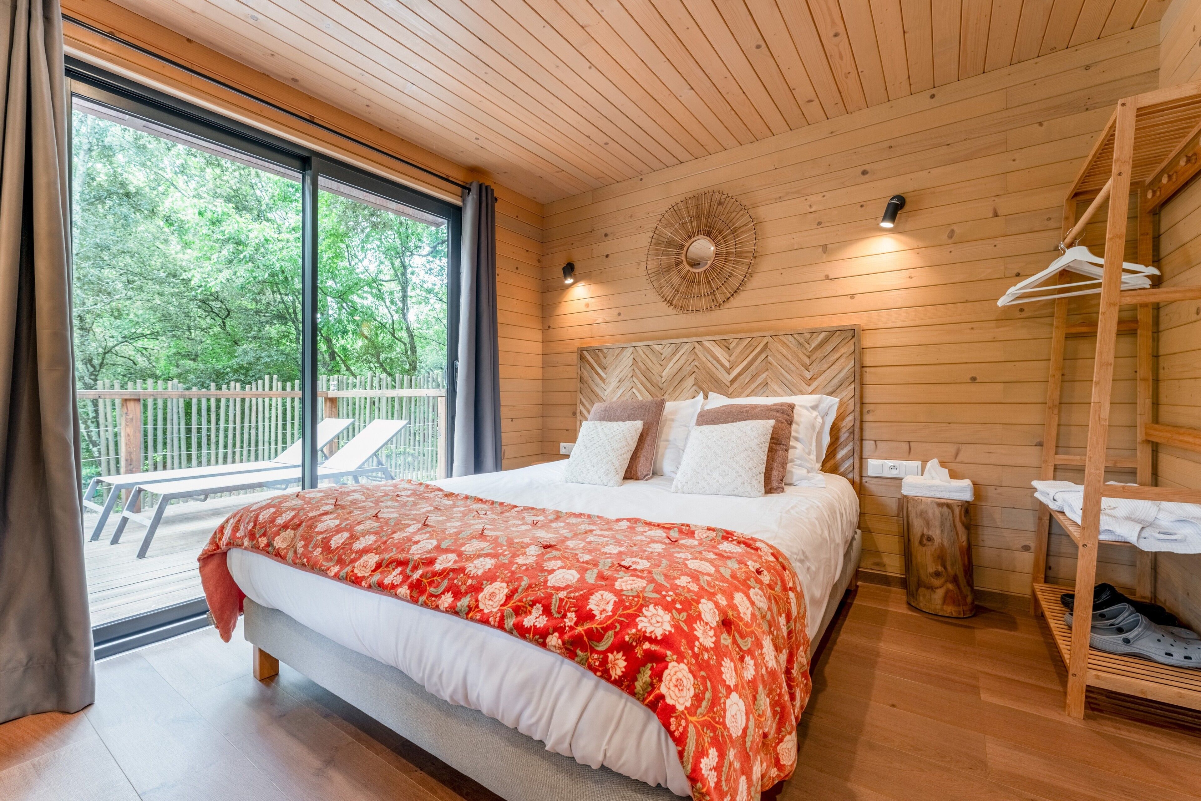 Een kamer met houten lambrisering, een bed en een houten plank, met uitzicht op de omgeving.