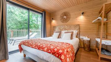 Een kamer met houten lambrisering, een bed en een houten plank, met uitzicht op de omgeving.