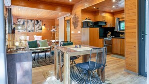 Un intérieur en bois comprenant un coin repas, une cuisine et une grande fenêtre.
