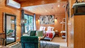 L'intérieur d'un chalet en bois comprend un lit, un coin salon et un miroir.