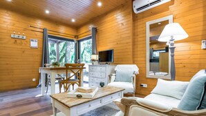 Una stanza con rivestimento in legno, un tavolo da pranzo, un divano, una TV e una lampada.