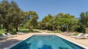 Une piscine avec des chaises longues et des arbres en arrière-plan.