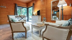 Una habitación con paneles de madera, un sofá, sillas, una mesa y un televisor.