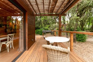 A wooden deck with a table and chairs, surrounded by trees.
