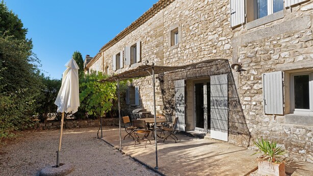 Un bâtiment en pierre doté d’un patio couvert, d’un espace extérieur aménagé pour s’asseoir et d’une allée en gravier.