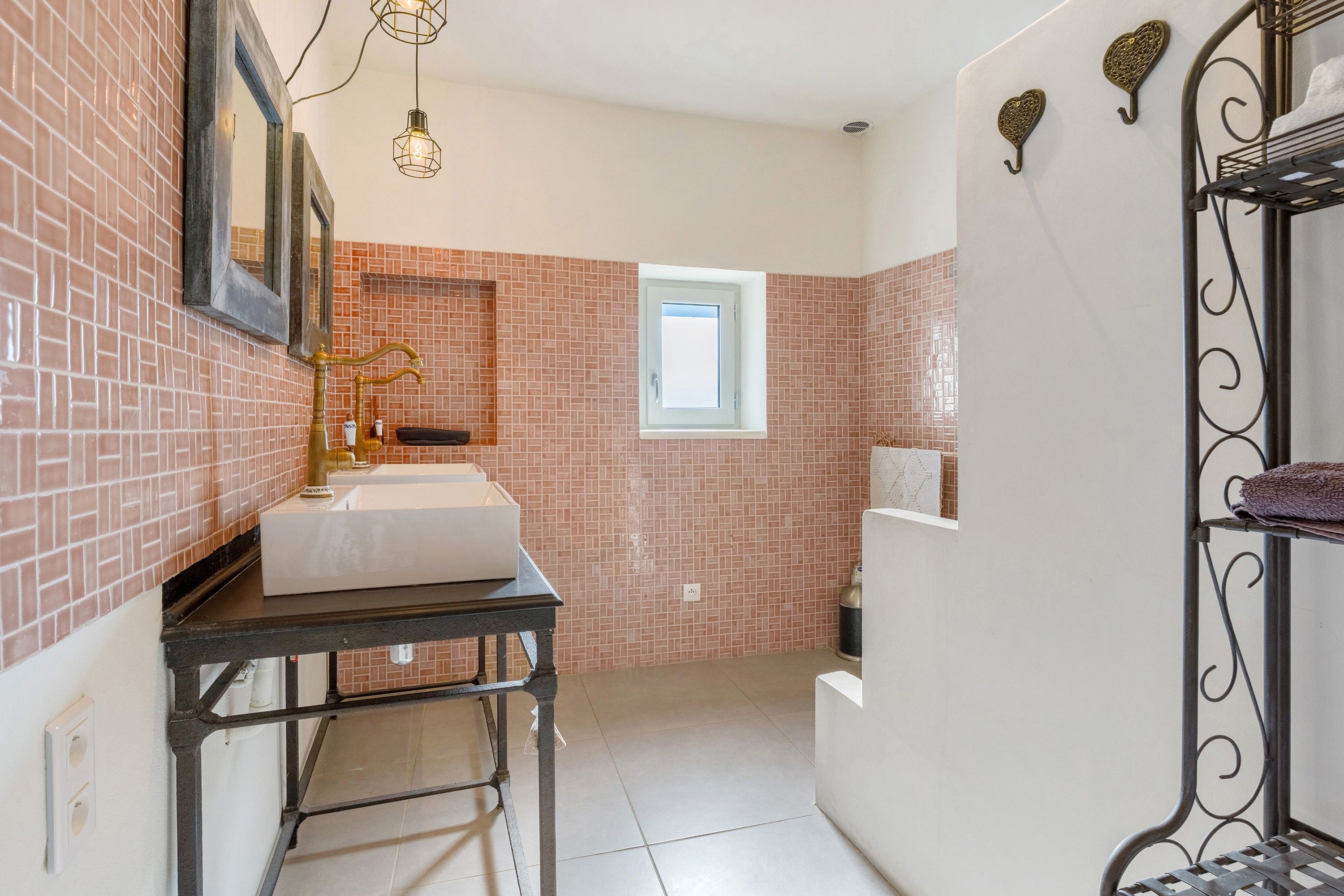 Une salle de bain avec un lavabo blanc, un miroir, une fenêtre et un porte-serviettes.