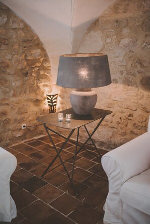 Ein Zimmer mit steinernen Wänden, einer Tischlampe, zwei Gläsern und einem kleinen Dekorationsobjekt.