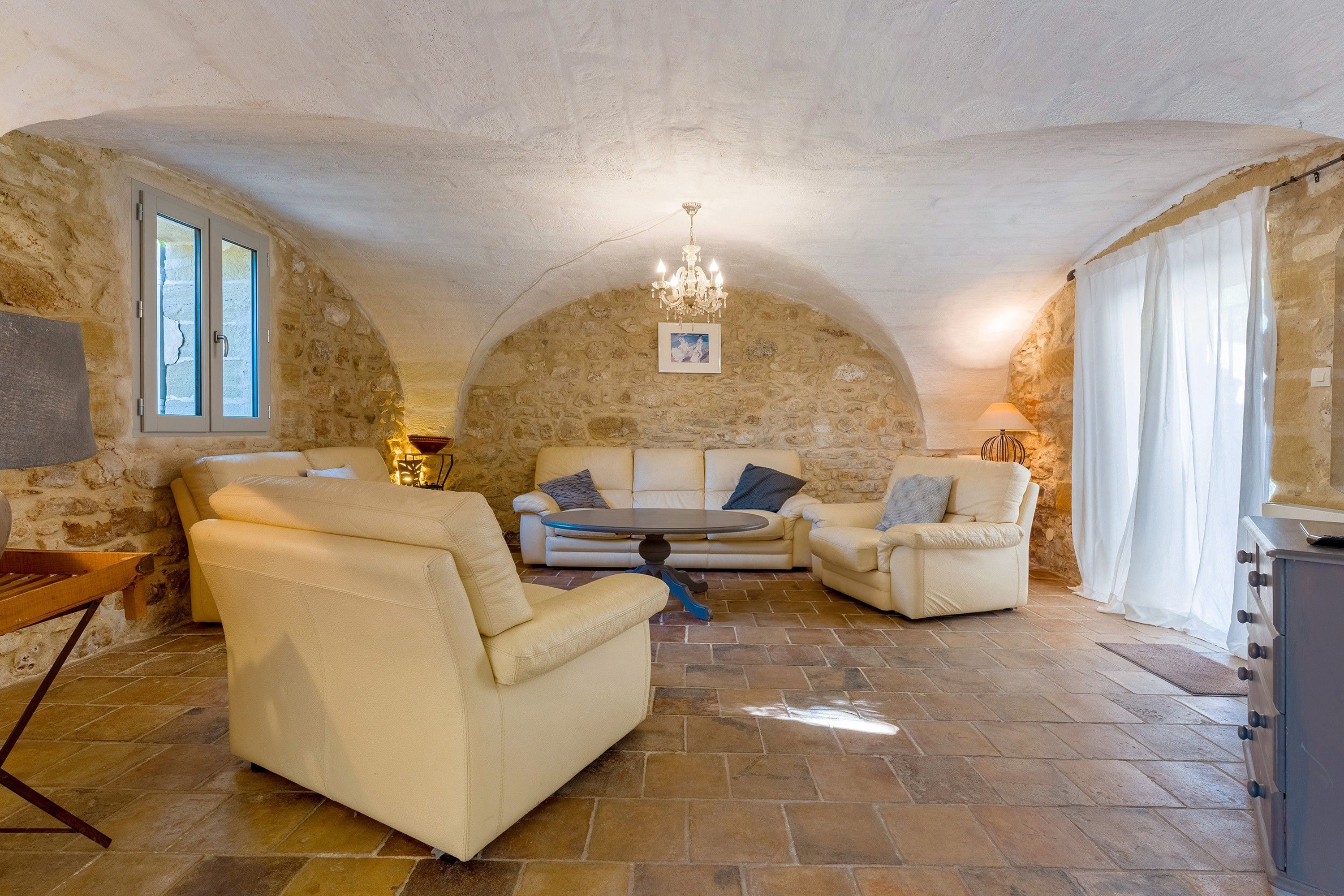 Un intérieur chaleureux avec des murs en pierre, un lustre et des sièges confortables.