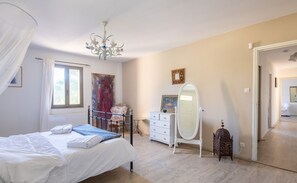 Une chambre à coucher avec un lit, une commode, un miroir et un lustre.