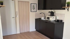 Una cocina compacta con armarios oscuros, un microondas, una tetera y una pequeña encimera.