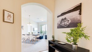 Un intérieur moderne comprenant un coin repas, une console noire agrémentée d’une plante et une œuvre d’art encadrée accrochée au mur.