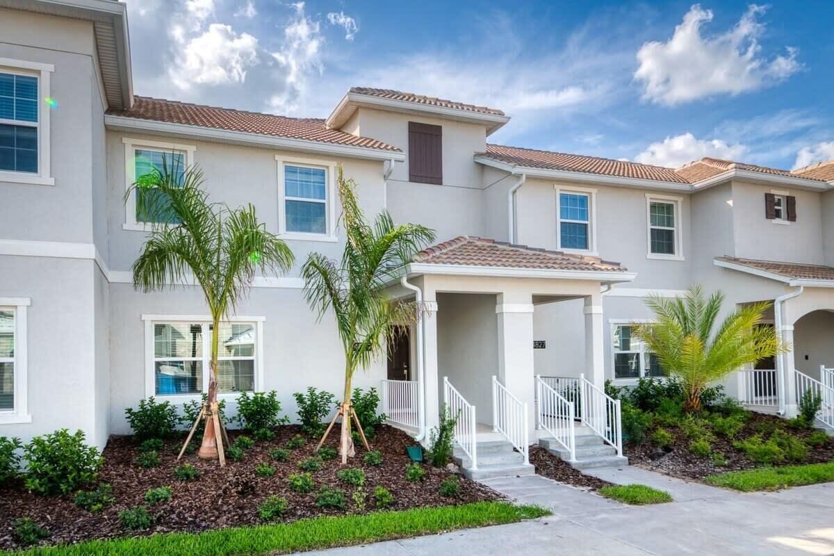 A residential building with multiple units, a covered porch, and a landscaped front yard.