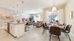 A modern kitchen with a central island, dining area with chairs, and a living room with a sofa. - Beautiful House, Great Location, Private Pool (Kissimmee)