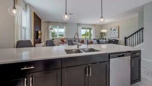 Uma cozinha moderna com ilha central, eletrodomésticos embutidos e iluminação pendente.