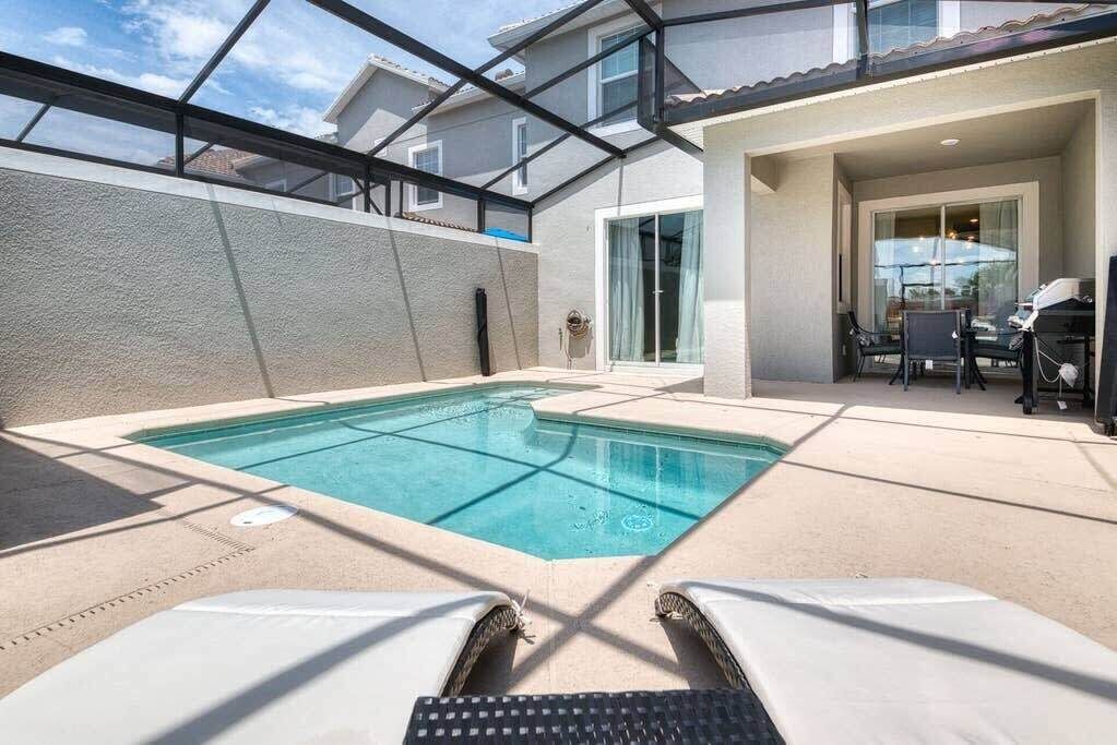 A swimming pool with lounge chairs, a glass ceiling, and a patio area.