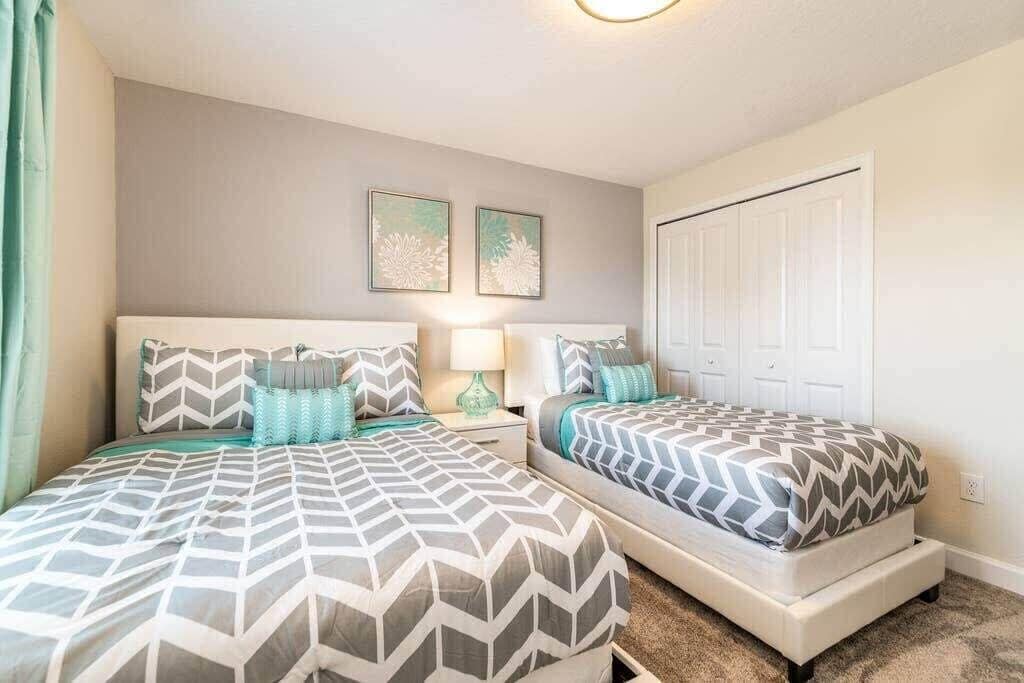A bedroom with two beds, a nightstand, a lamp, and two framed pictures on the wall.