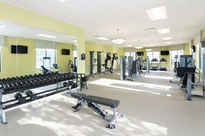 Ett gym med olika typer av träningsutrustning, inklusive hantlar, bänkar och styrketräningsmaskiner.