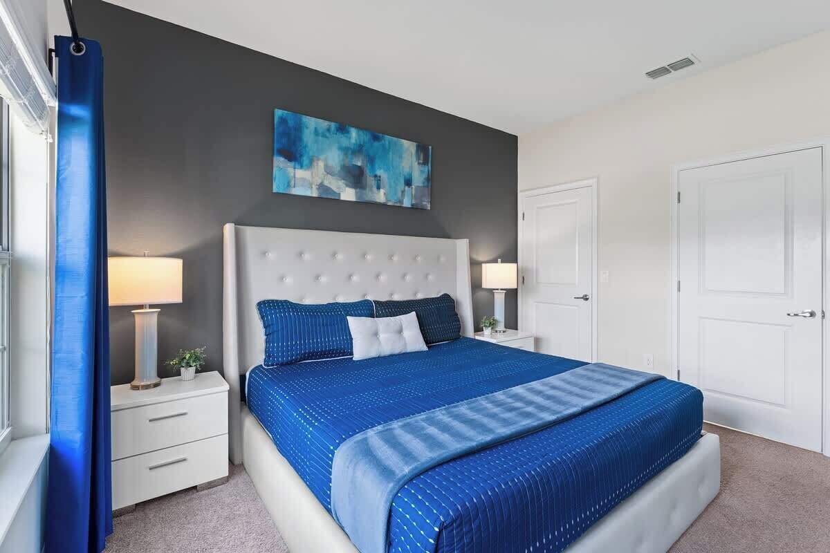 Una camera da letto con un letto grande, due comodini, una finestra con tende e un quadro appeso al muro.