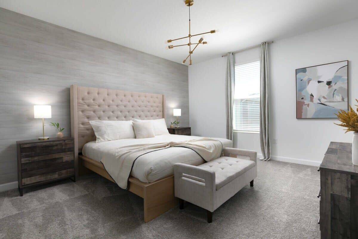 A modern bedroom with a tufted headboard, bedside lamps, a bench, and a large abstract painting.