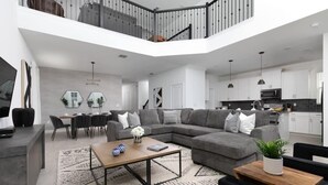 A modern living room with a sectional sofa, a coffee table, and a dining area with chairs and a table. - Chic & Spacious Best Vacation Home (Kissimmee)