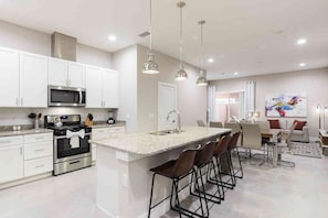 A modern kitchen with white cabinets, stainless steel appliances, and a central island with bar stools.