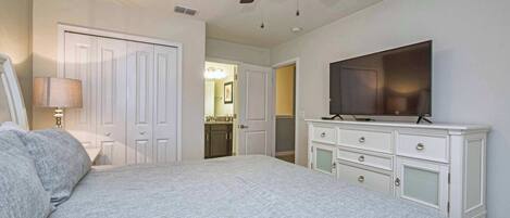 A bedroom with a bed, a dresser, a television, and a ceiling fan.