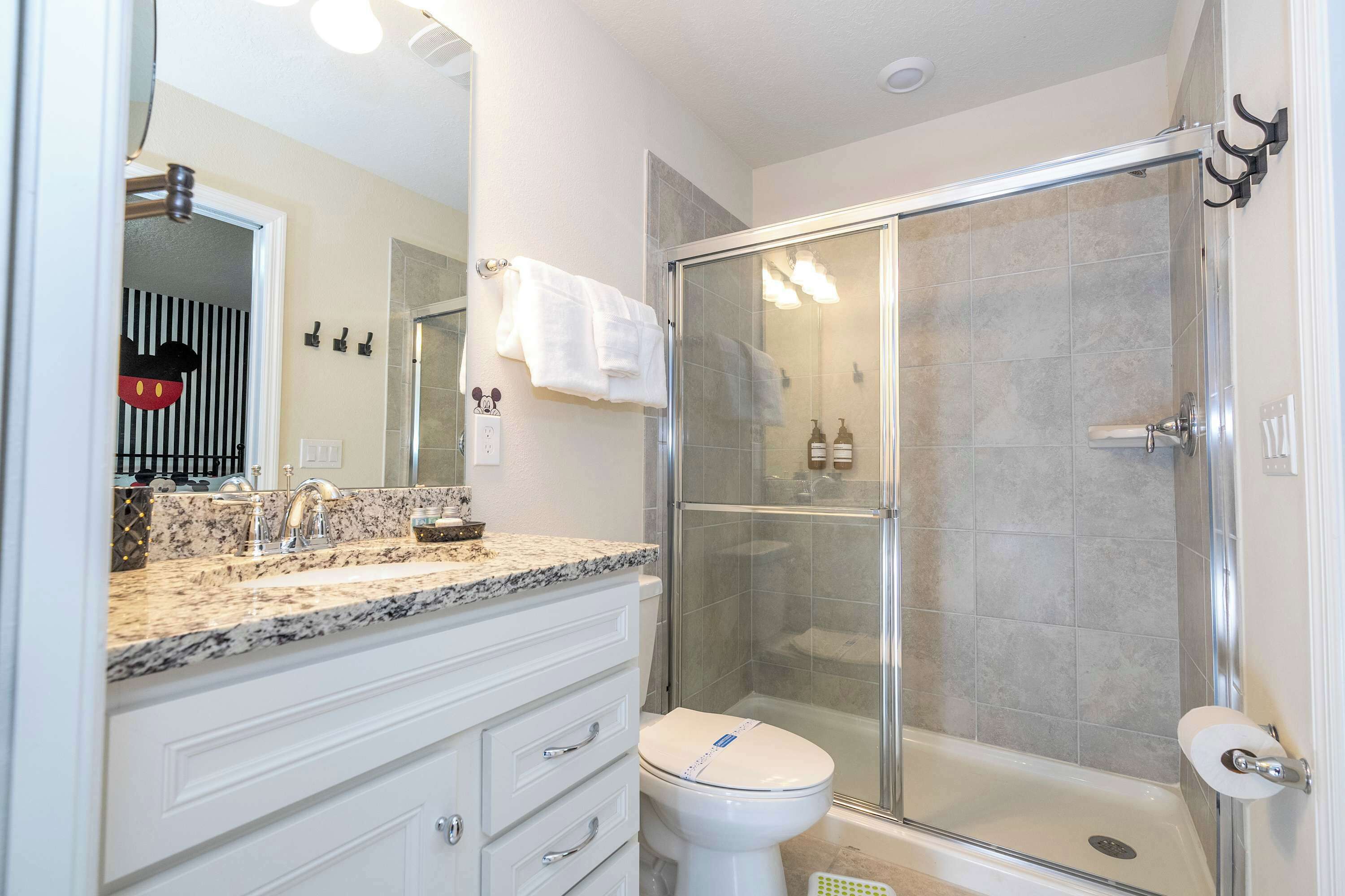 A bathroom with a shower, toilet, and vanity with drawers.