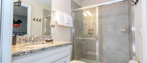 A bathroom with a shower, toilet, and vanity with drawers.