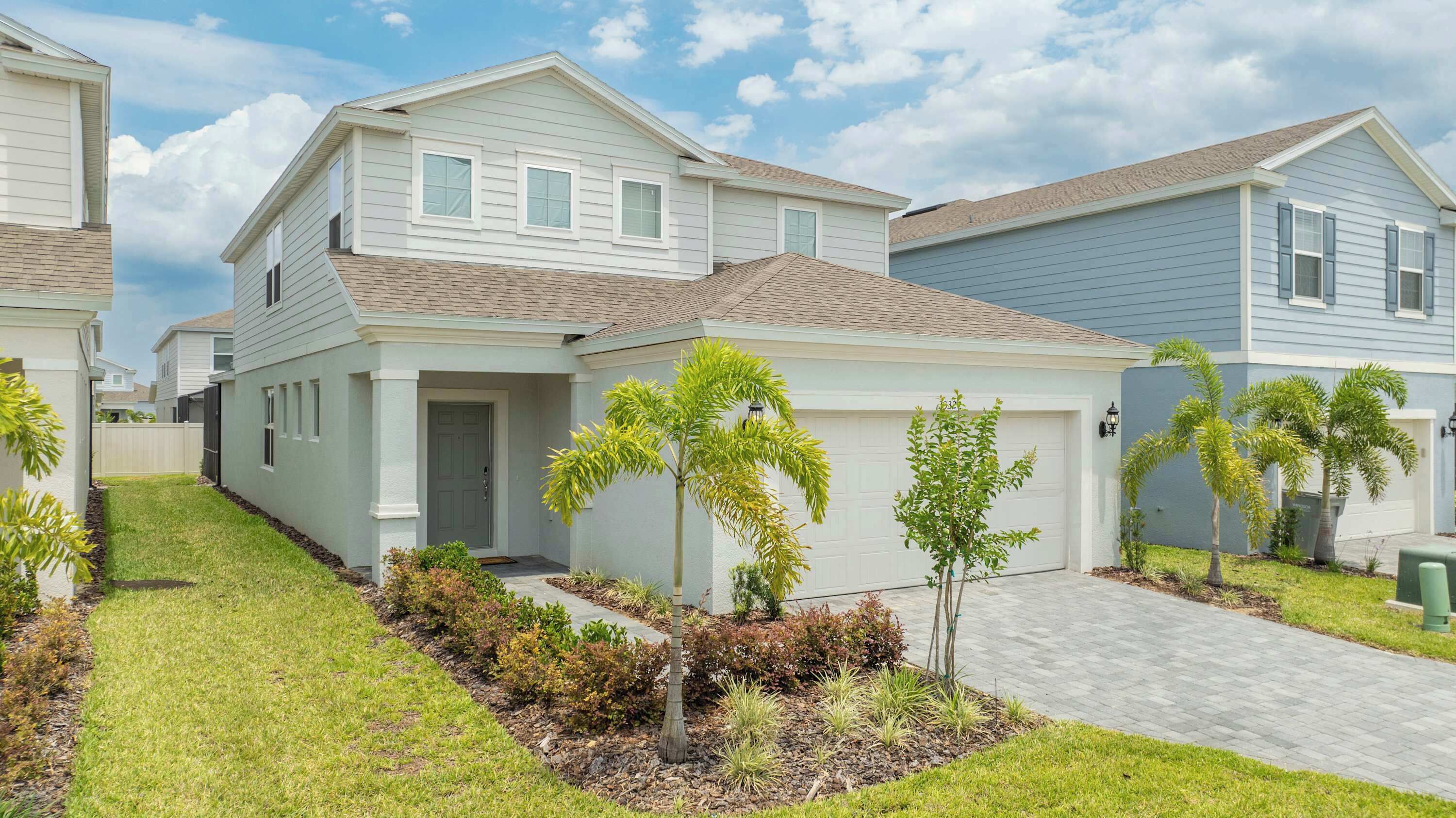 A residential area with houses, a paved driveway, and small trees.