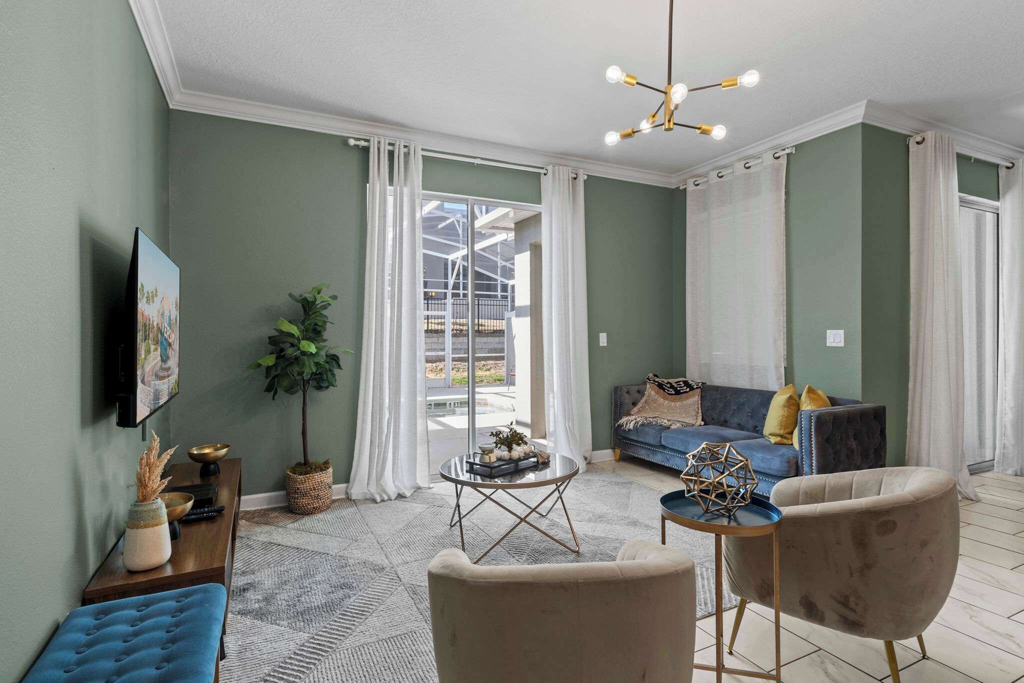 A living room with a sofa, two armchairs, a coffee table, a TV, and a large window with curtains.