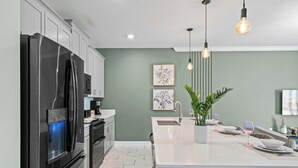 A modern kitchen with a large island, stainless steel appliances, and pendant lighting. - Chic 4BR Home With Mickey & Star Wars Rooms (Davenport)