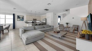 Uma sala de estar moderna com um sofá seccional, uma mesa de centro e uma televisão sobre um suporte.