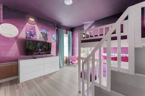Habitación infantil con literas, televisor, escritorio y silla.