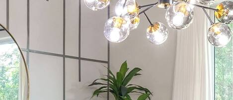 Un comedor con una mesa de madera dispuesta para cuatro, sillas tapizadas en azul, una planta en maceta y una lámpara de techo moderna.