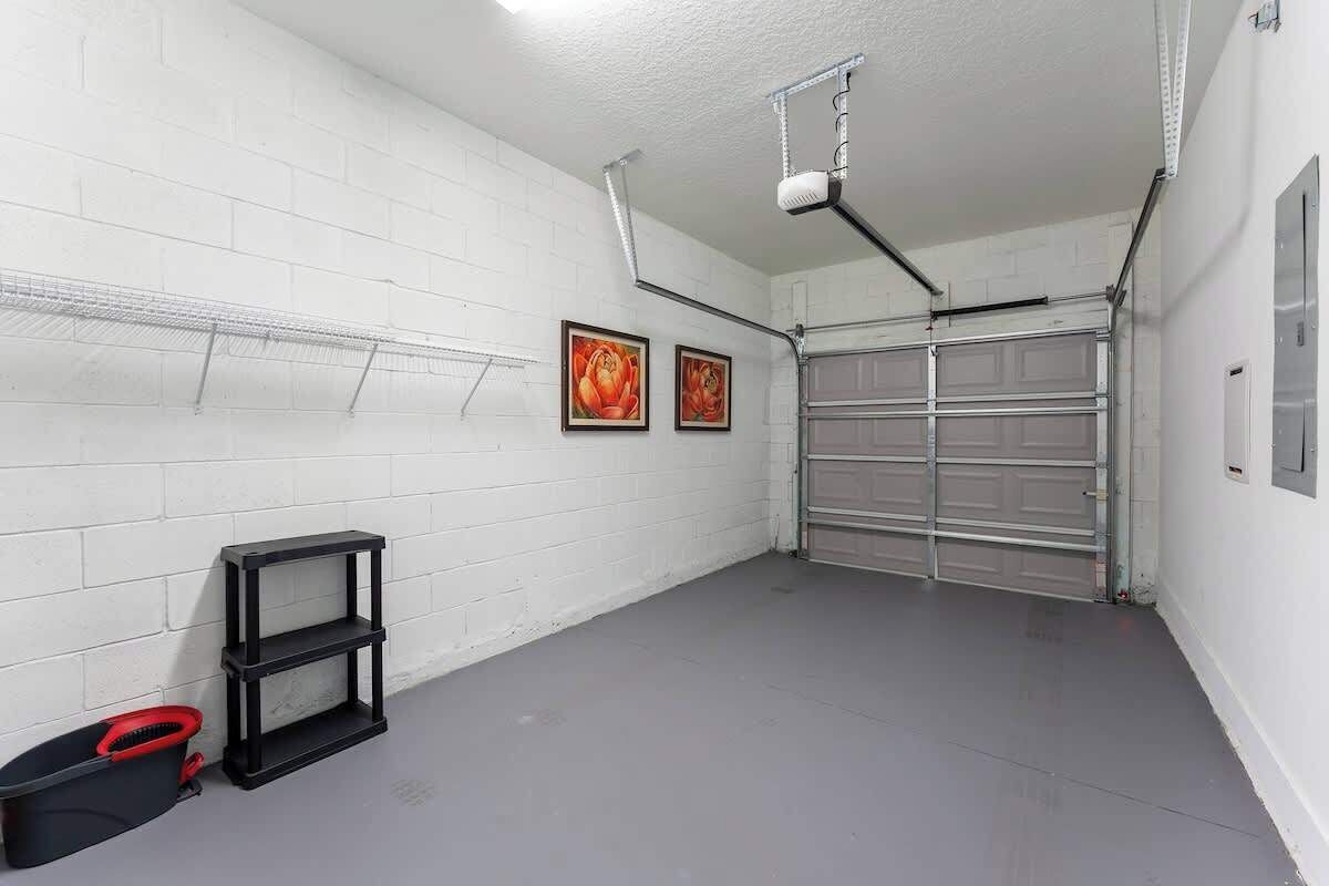 A garage with a white brick wall, a metal garage door, and a ceiling-mounted light fixture.