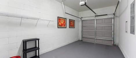 A garage with a white brick wall, a metal garage door, and a ceiling-mounted light fixture.