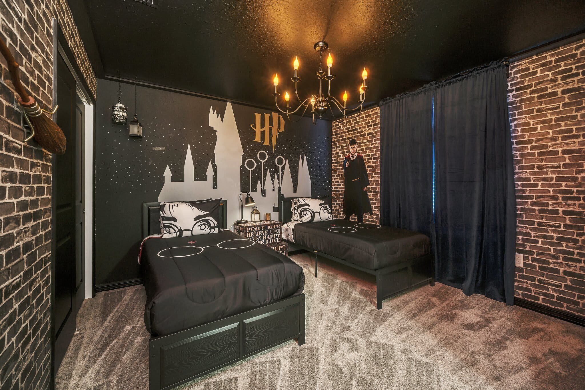 A bedroom with two beds, a chandelier, a brick wall, and a mural.