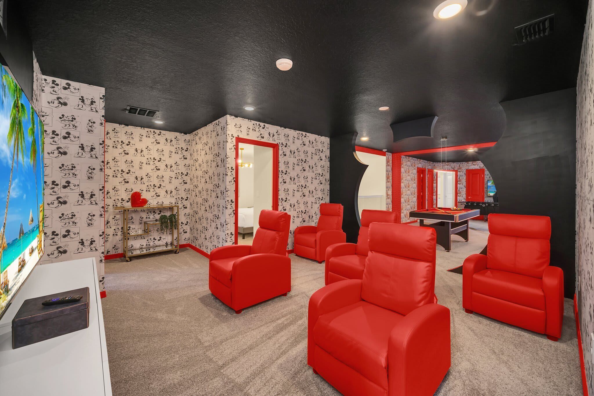 Una habitación con sillas rojas, una mesa y un televisor.