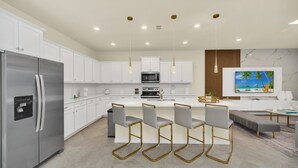 A modern kitchen with white cabinets, stainless steel appliances, and a central island with bar stools. - Chic 10br Retreat With Themed Rooms & Pool (Clermont)