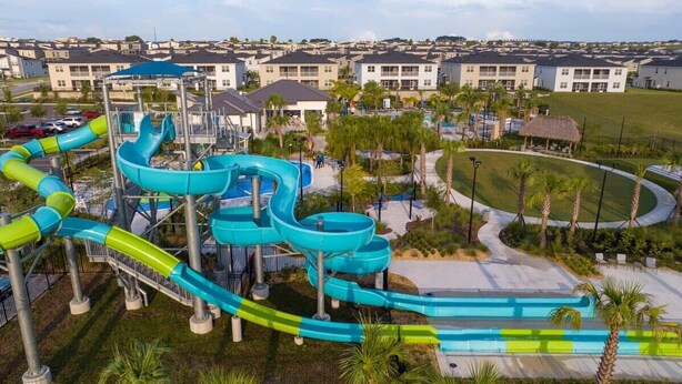 A water park with multiple slides and a pool area, surrounded by residential buildings. - Champions Gate Oasis, 4BR Vacation Haven (Davenport)