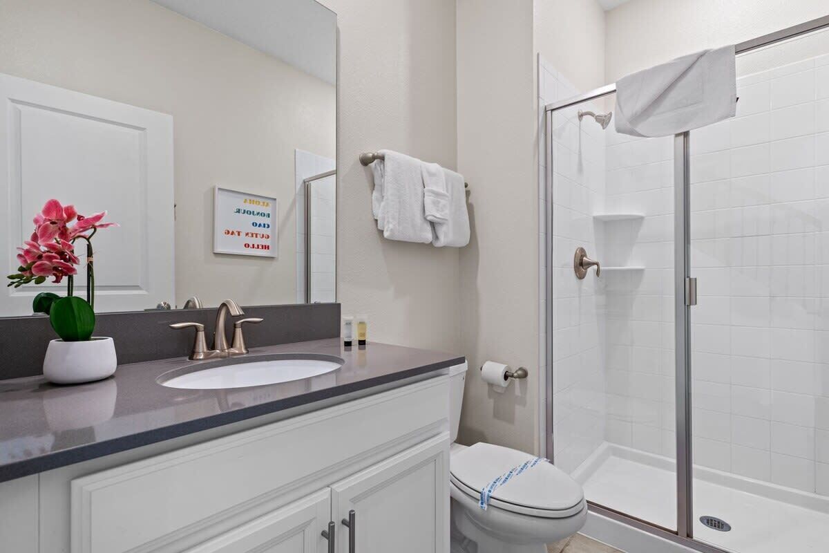 Une salle de bain équipée d’un lavabo, d’un miroir, de toilettes et d’une douche.