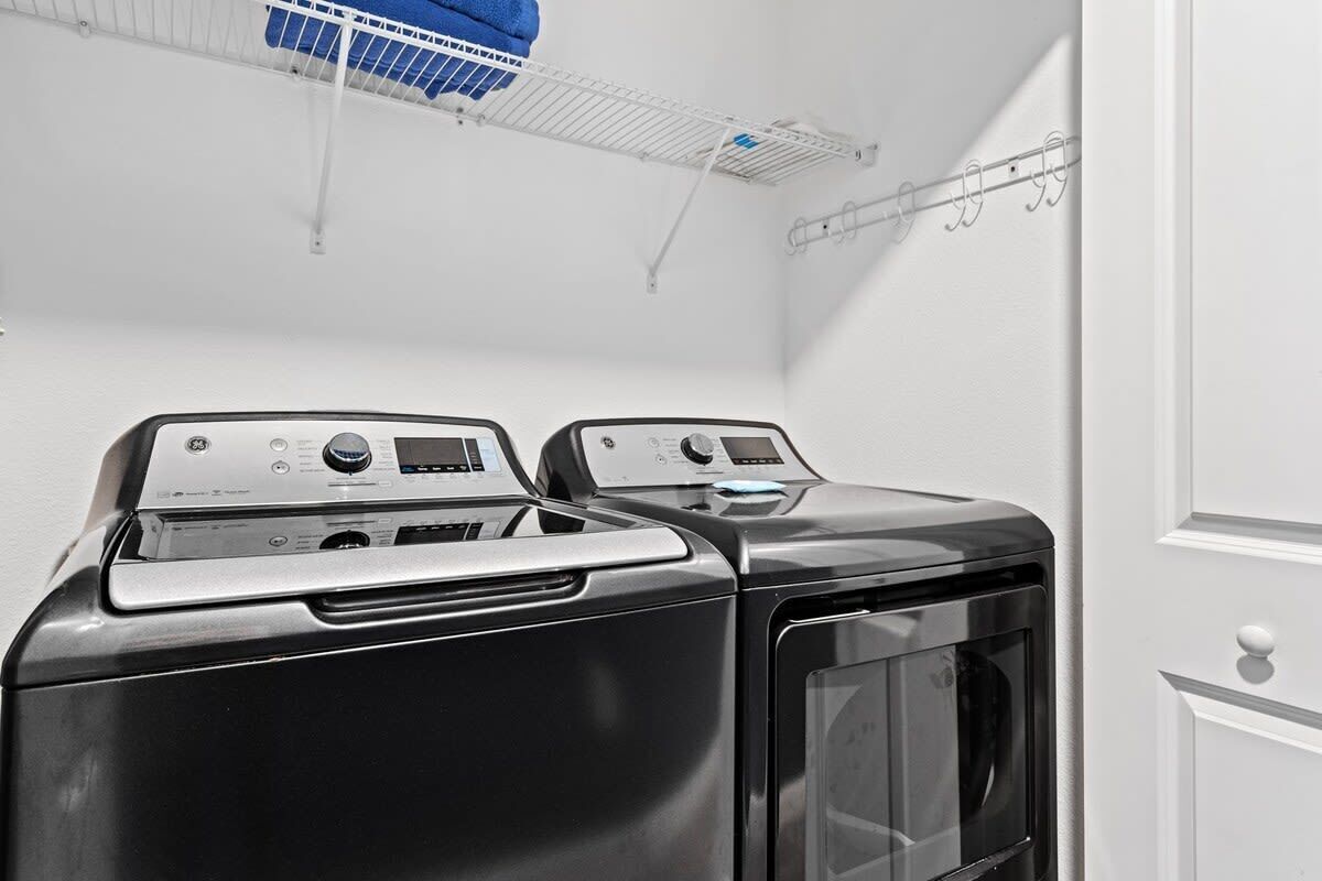 A laundry room with two front-loading washing machines and a drying rack.