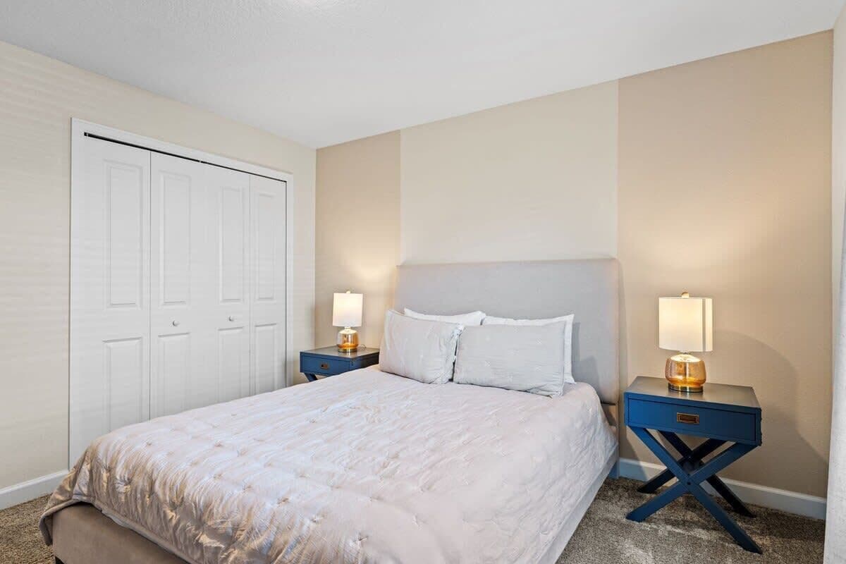 A bedroom with a bed, nightstands, a dresser, and a closet.