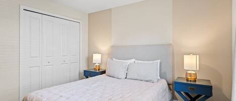 A bedroom with a bed, nightstands, a dresser, and a closet.